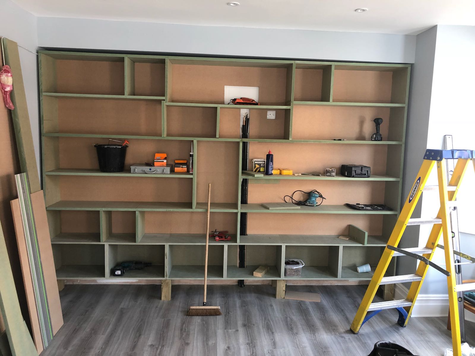 A room with a lot of shelves and a yellow ladder