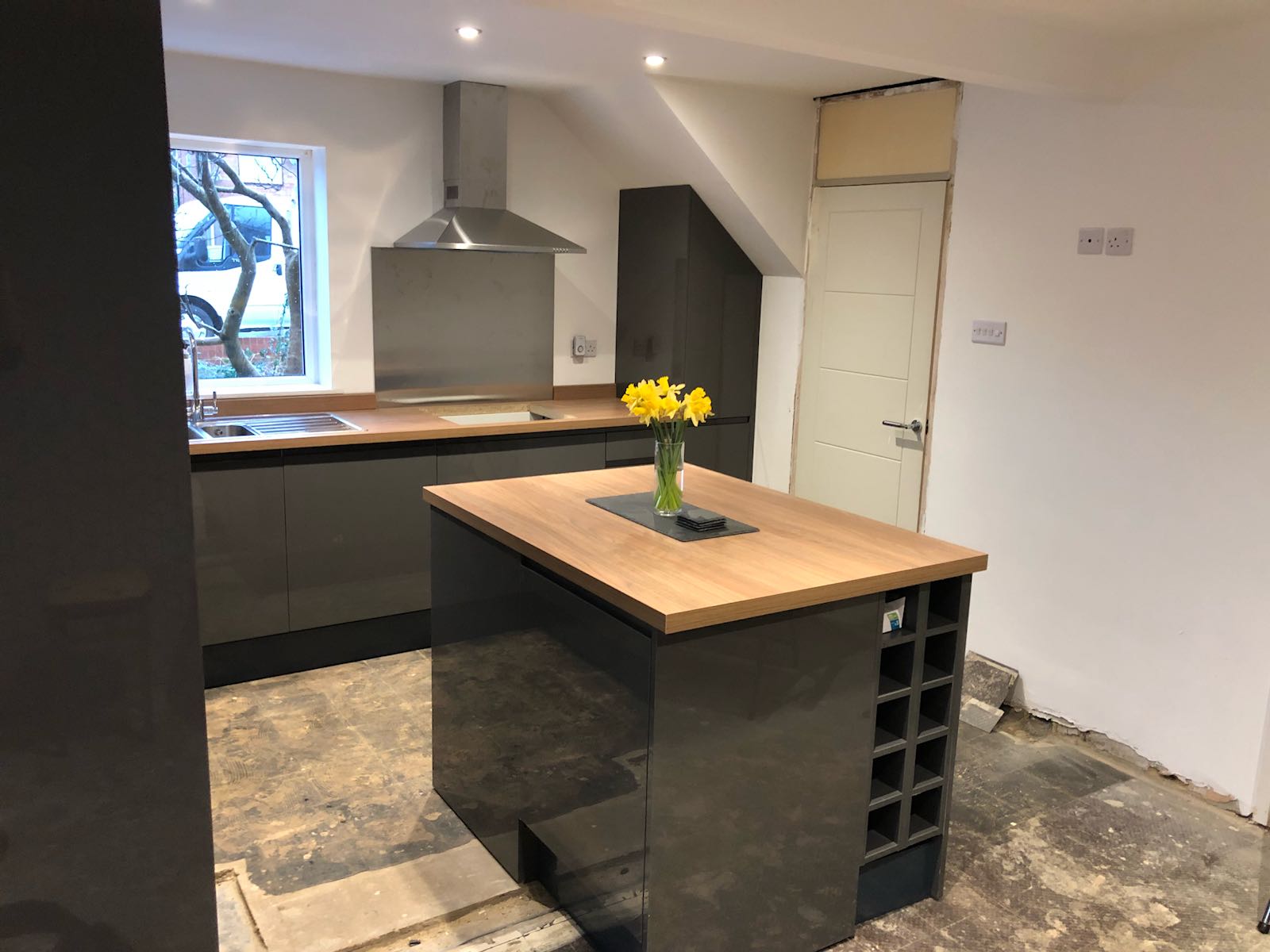 A kitchen with a large island and a vase of yellow flowers on it.