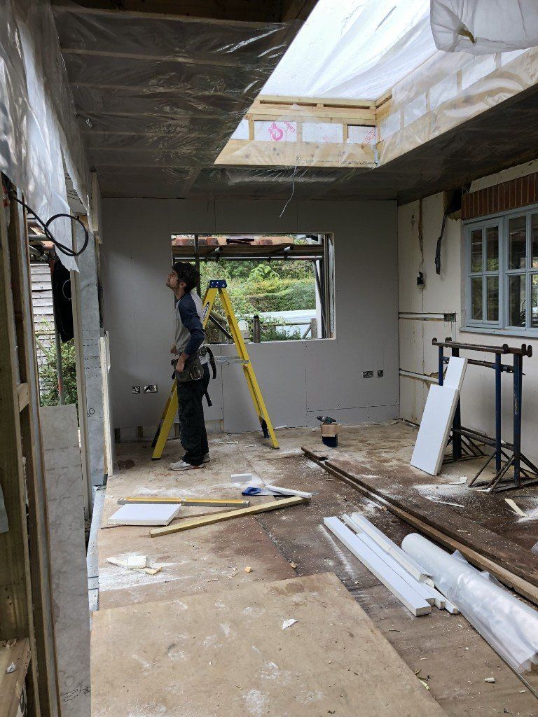A man is standing next to a ladder in a room under construction.