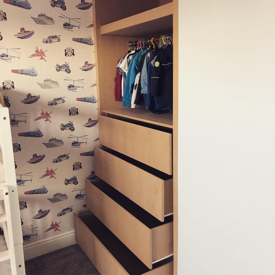 A closet with drawers and a wall with cars on it
