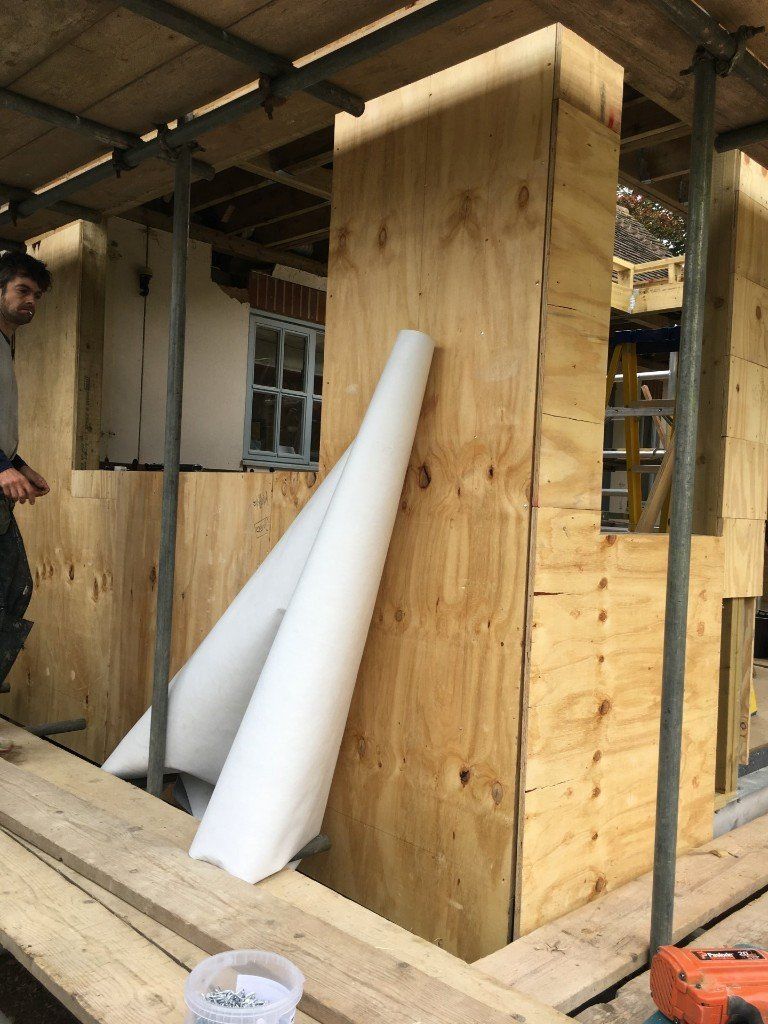 A man is standing on a scaffolding next to a wooden wall.