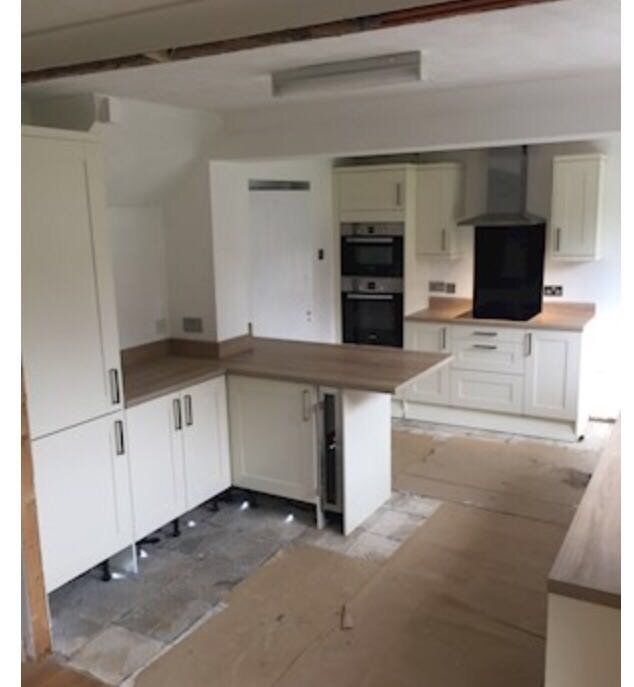 A kitchen with white cabinets and a wooden counter top