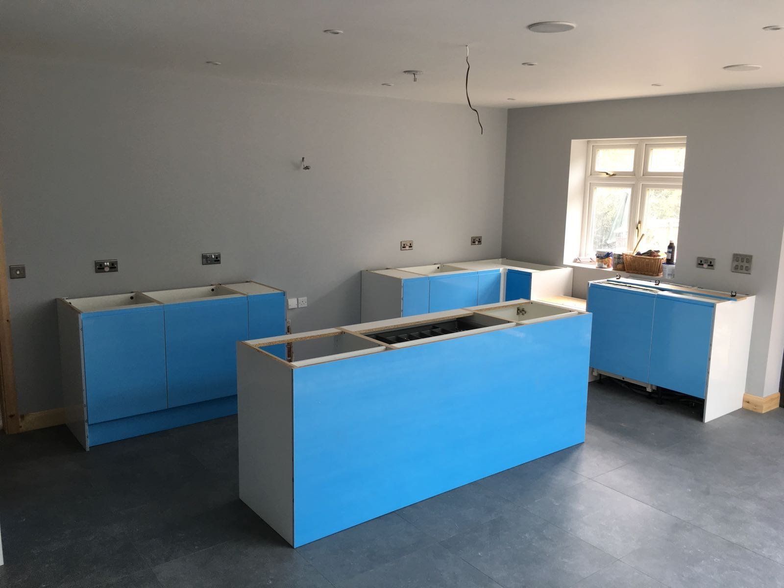 A kitchen with blue cabinets and white counter tops is being built.