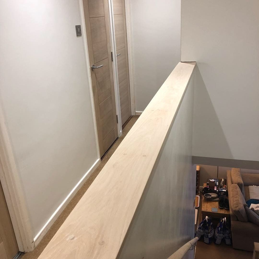 A hallway with a wooden railing leading to a living room.