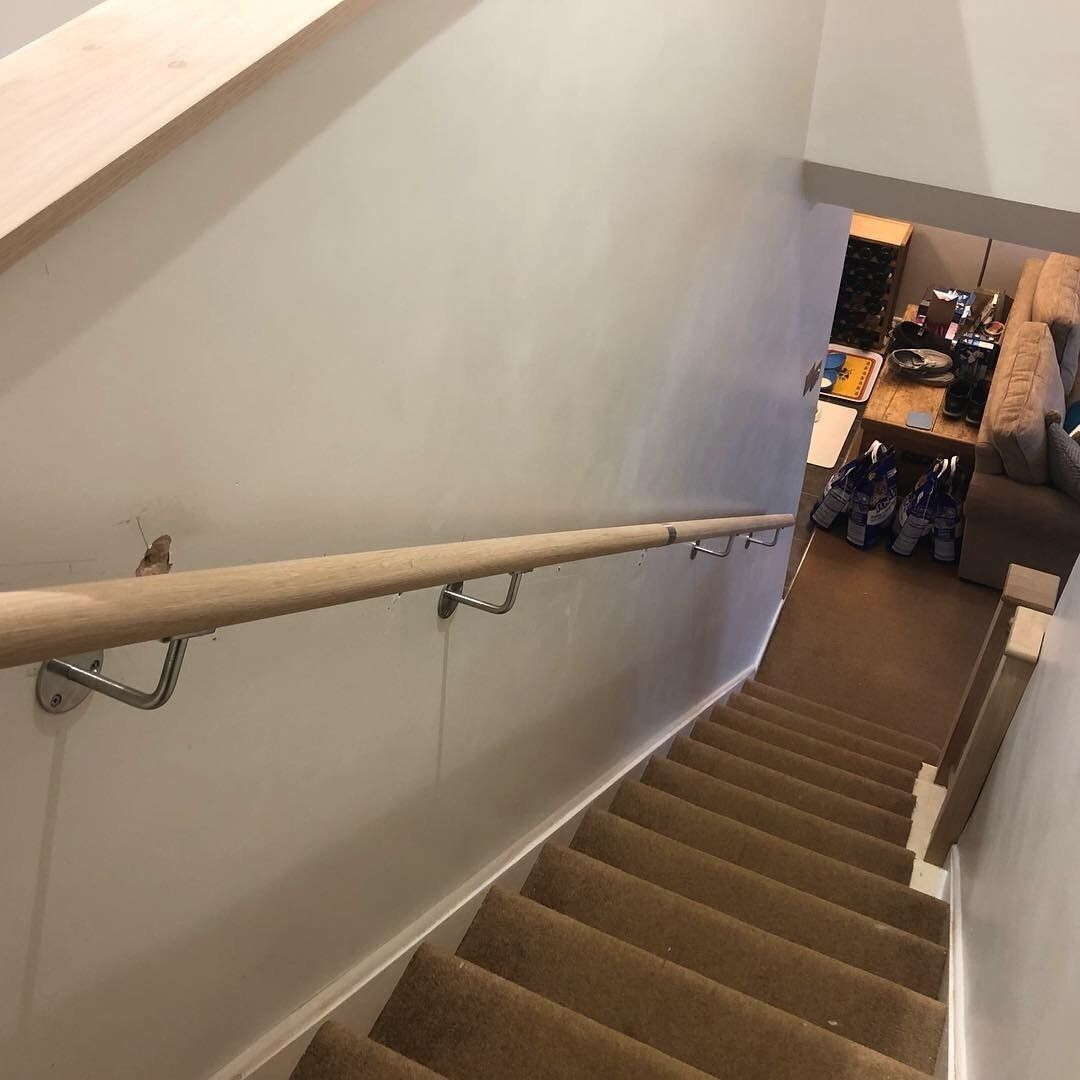 A staircase with a wooden handrail leading up to a living room.