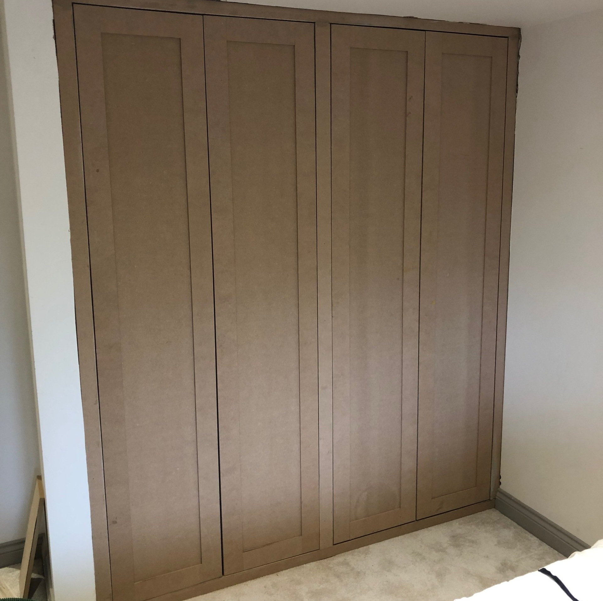 A bedroom with a large wooden wardrobe and a bed.