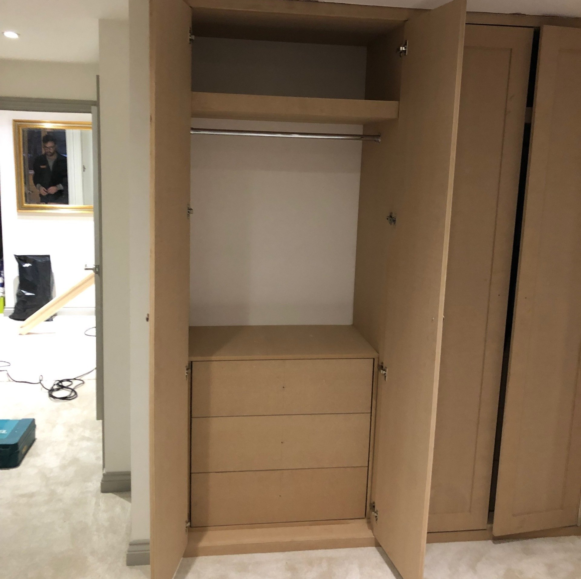 A closet with the door open and a picture on the wall behind it