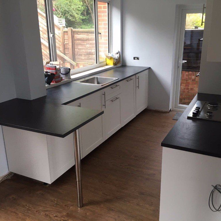 A kitchen with black counter tops and white cabinets