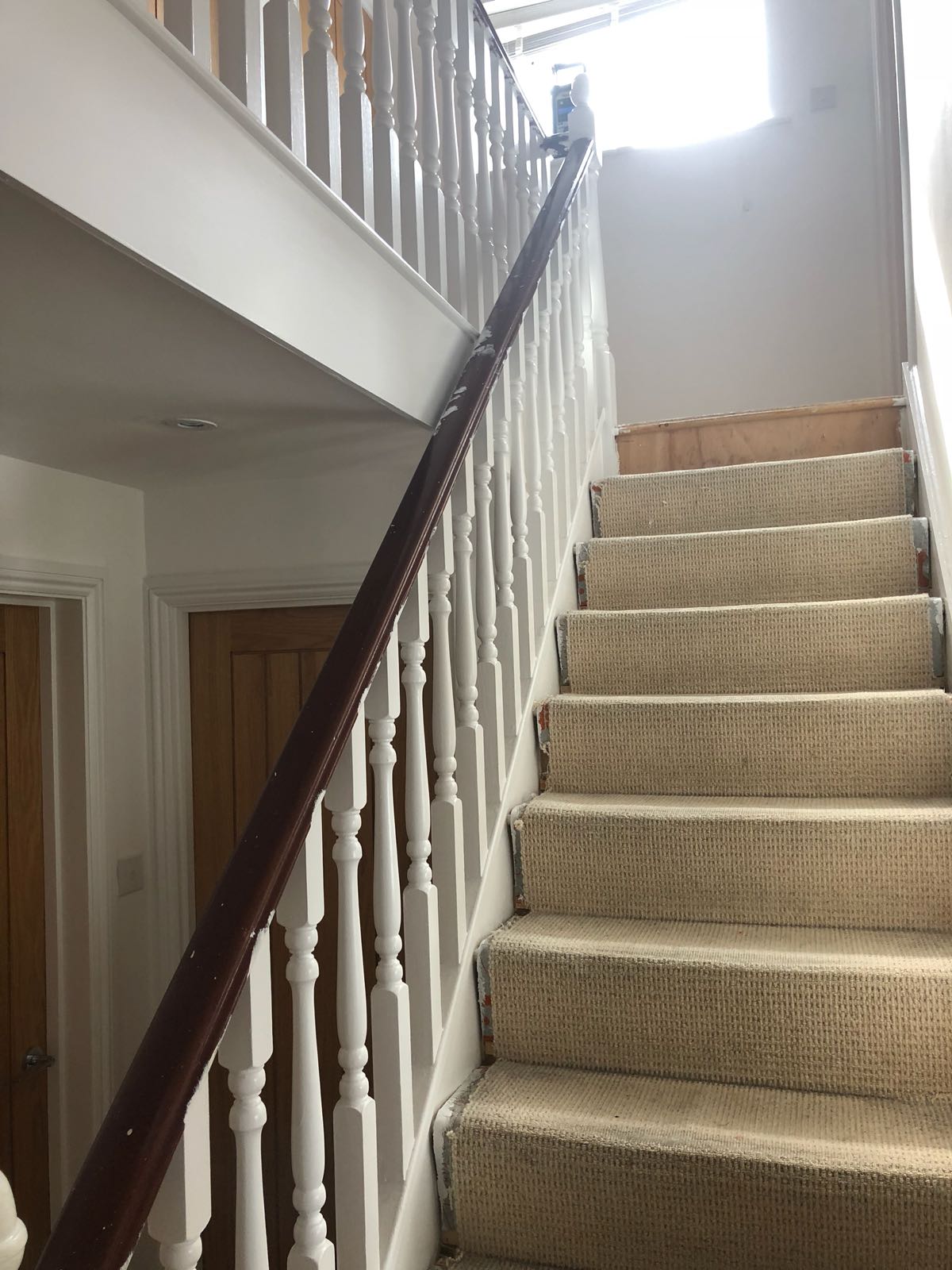 A staircase with a wooden railing and a carpeted staircase.
