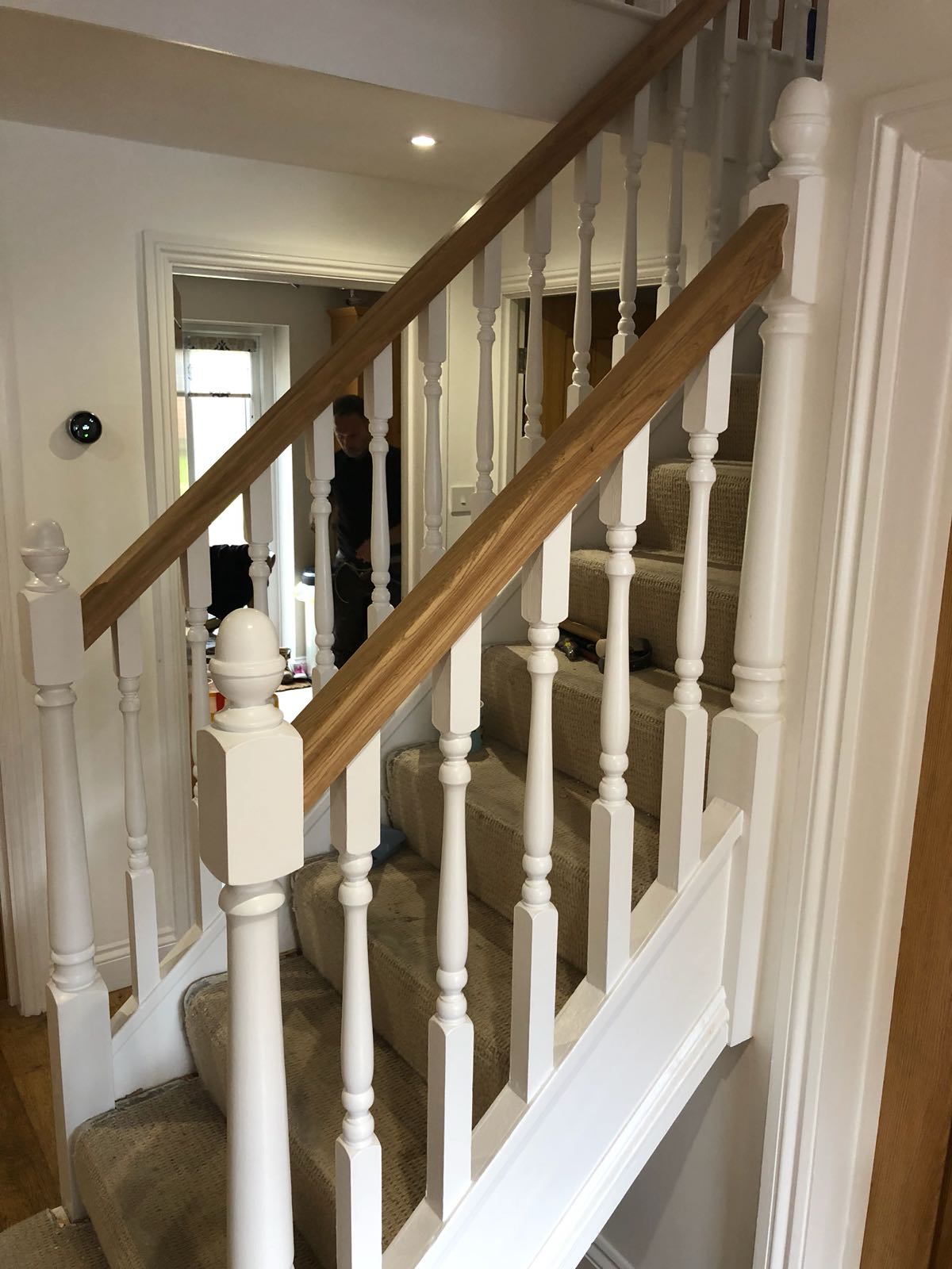 A white staircase with a wooden railing and a carpeted staircase.