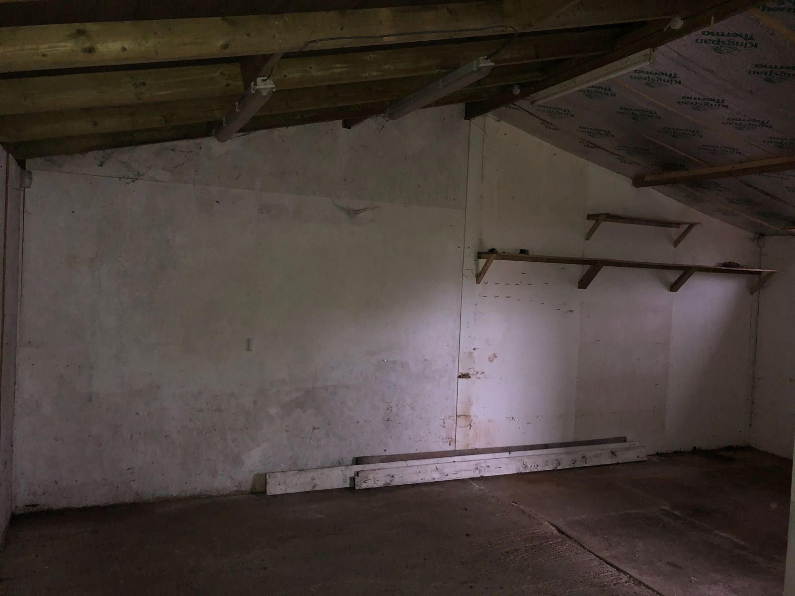 An empty room with a wooden ceiling and a white wall.