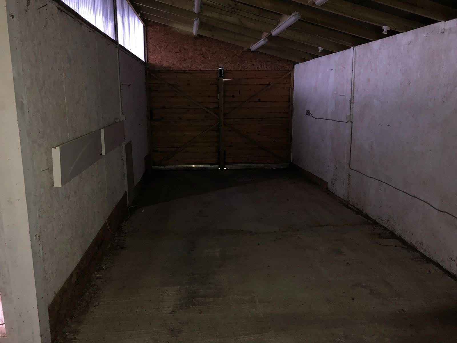 An empty garage with a wooden door and a brick wall.