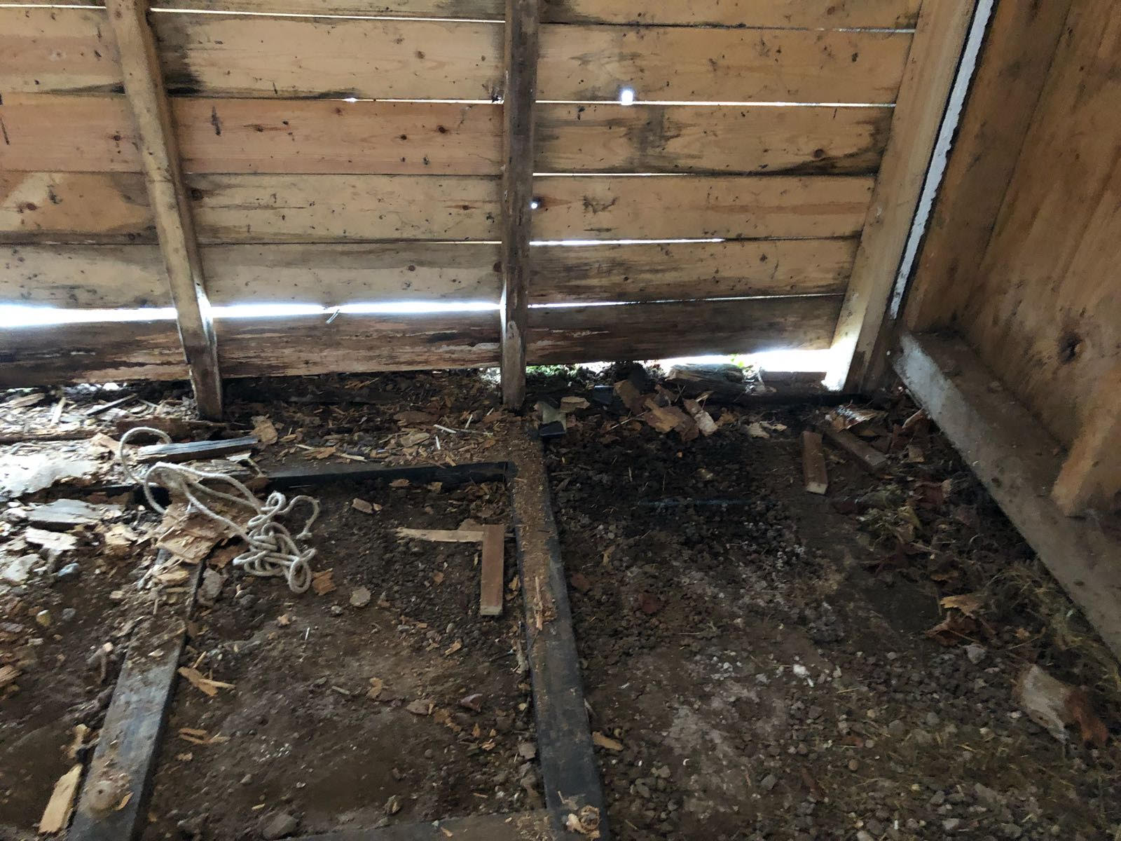 A wooden shed with a lot of wood shavings on the floor.