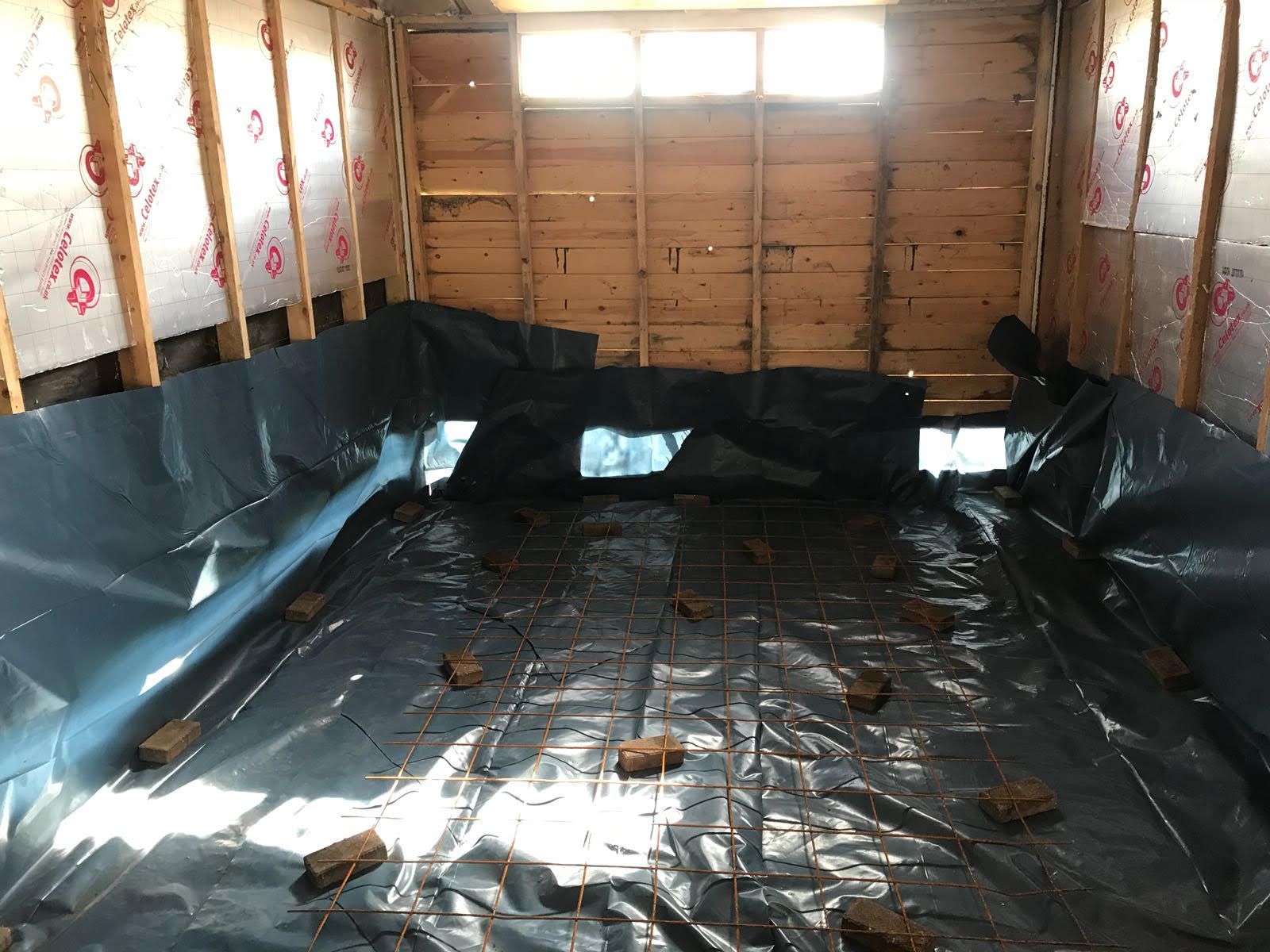 A room with a lot of plastic on the floor and bricks on the floor.