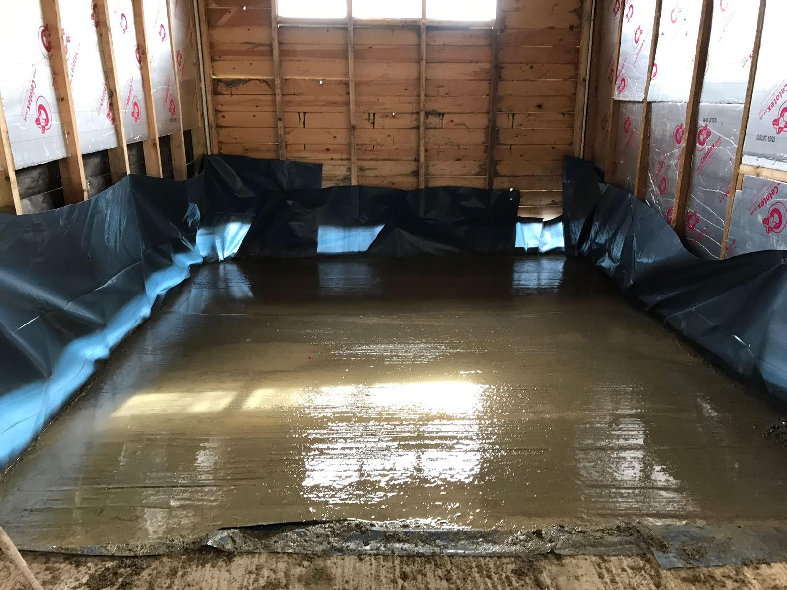 A room with a concrete floor and a wooden wall.