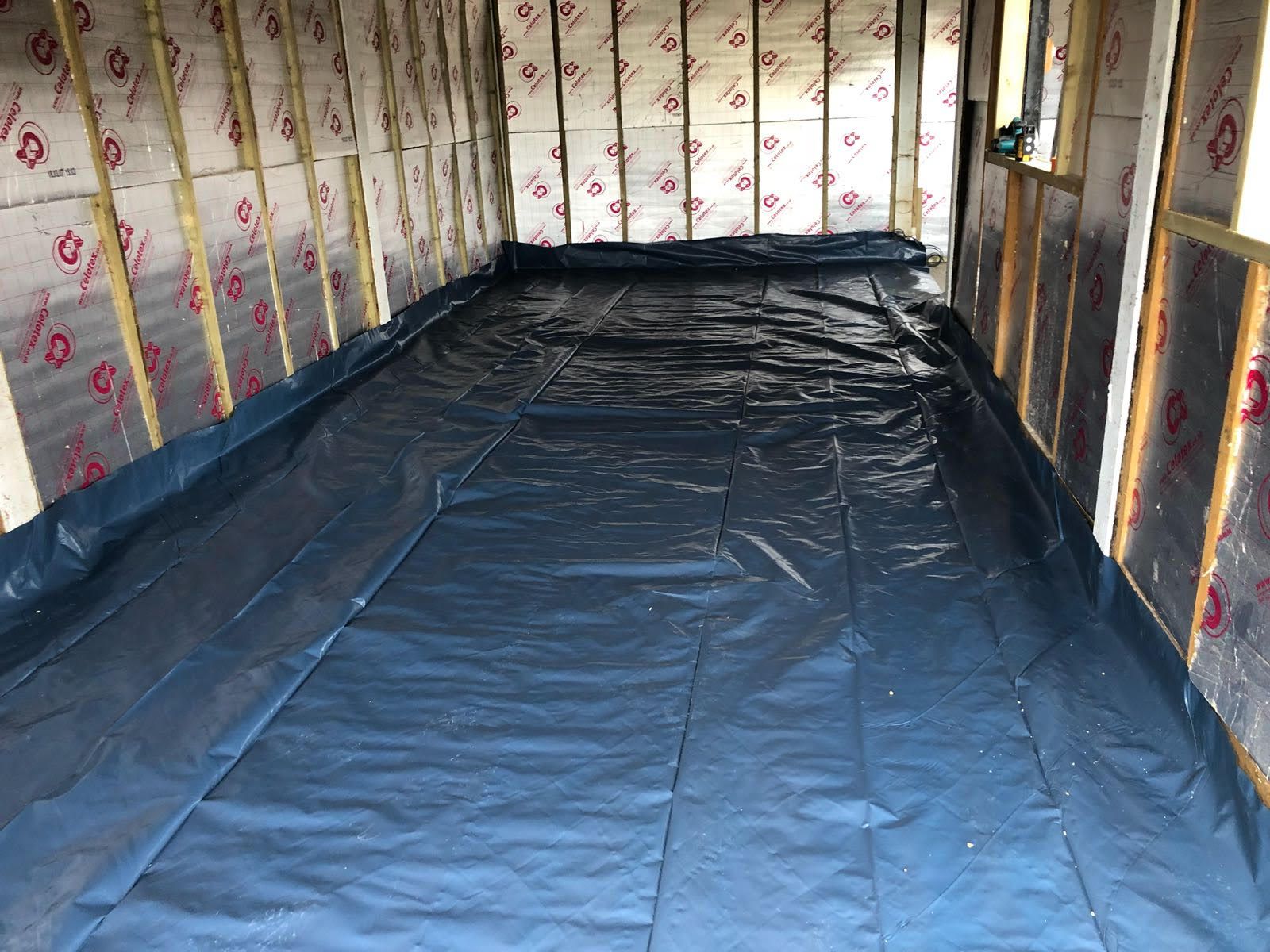A room with a blue tarp on the floor and walls.