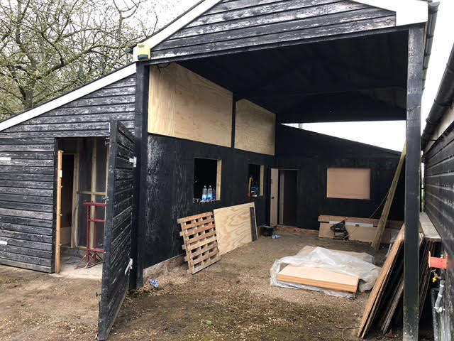 A black building with a large open door is being built.