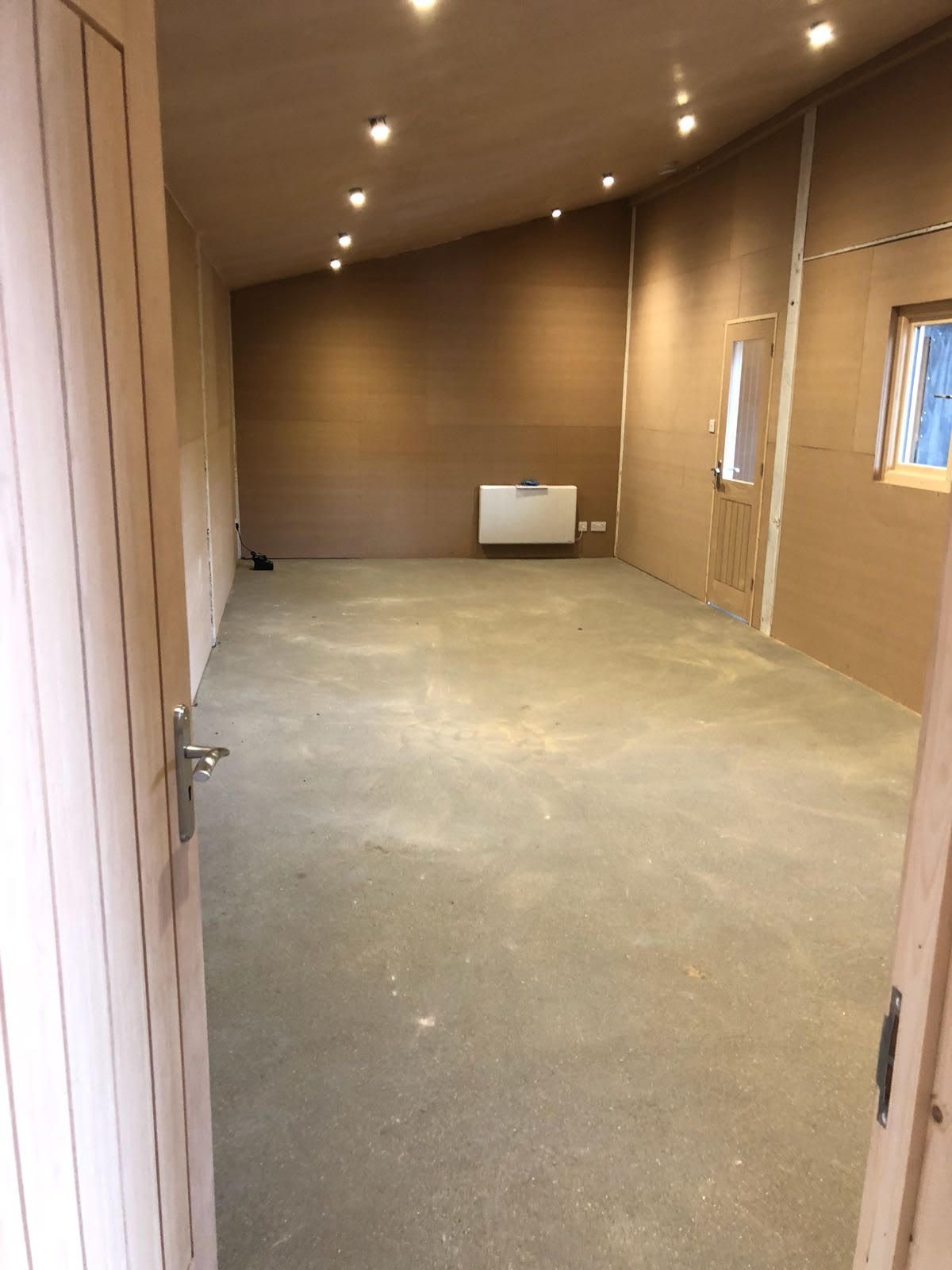 A large empty room with a concrete floor and a window.