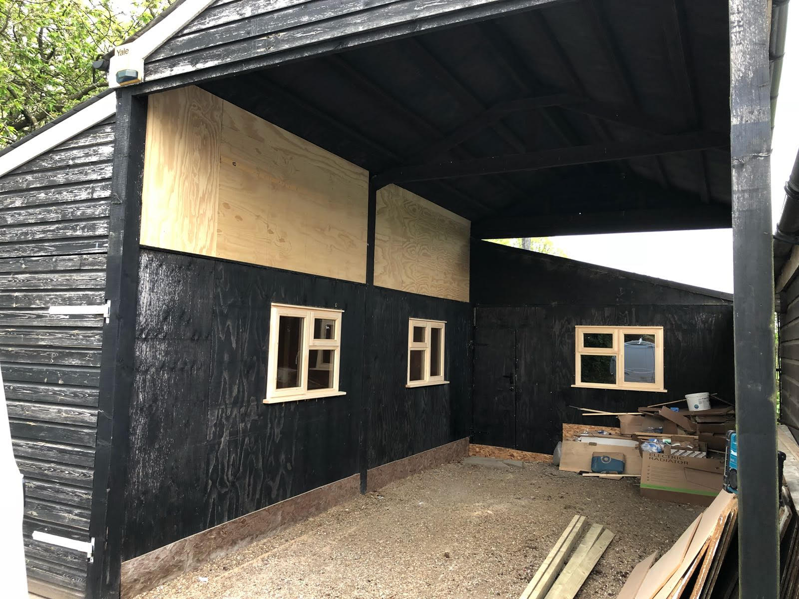 A black shed with wooden windows is being built.