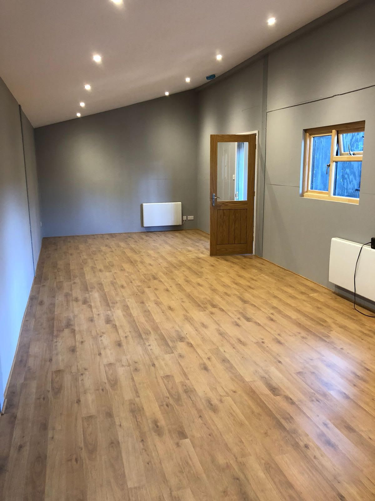 An empty room with a wooden floor and a window.