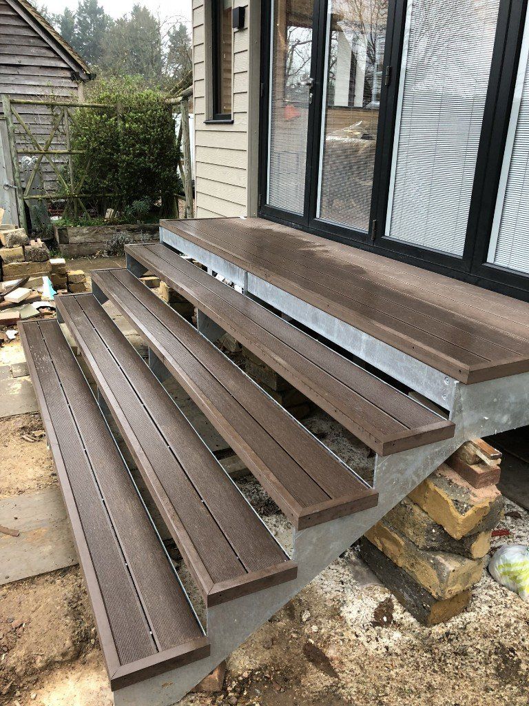 A set of wooden stairs leading up to a porch of a house.