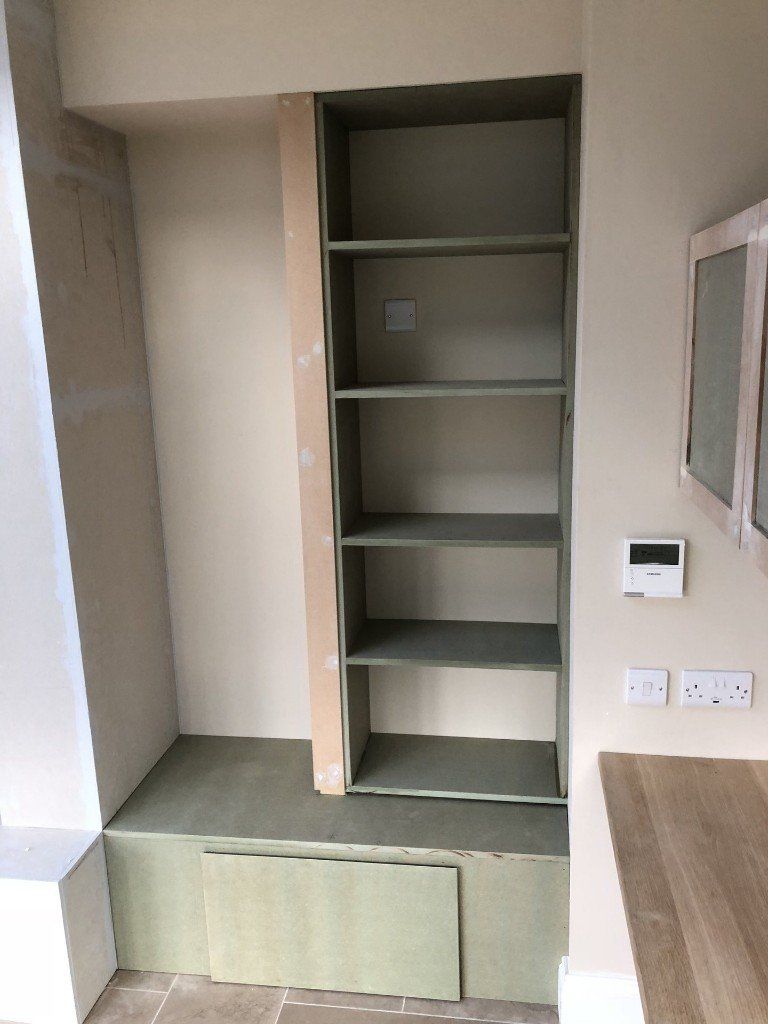 A room with a shelf and a thermostat on the wall.