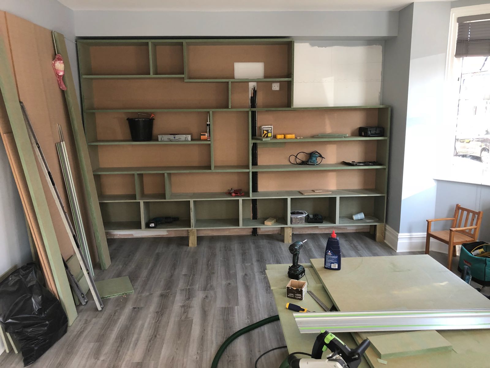 A room with a lot of shelves and a table with a vacuum cleaner in it.