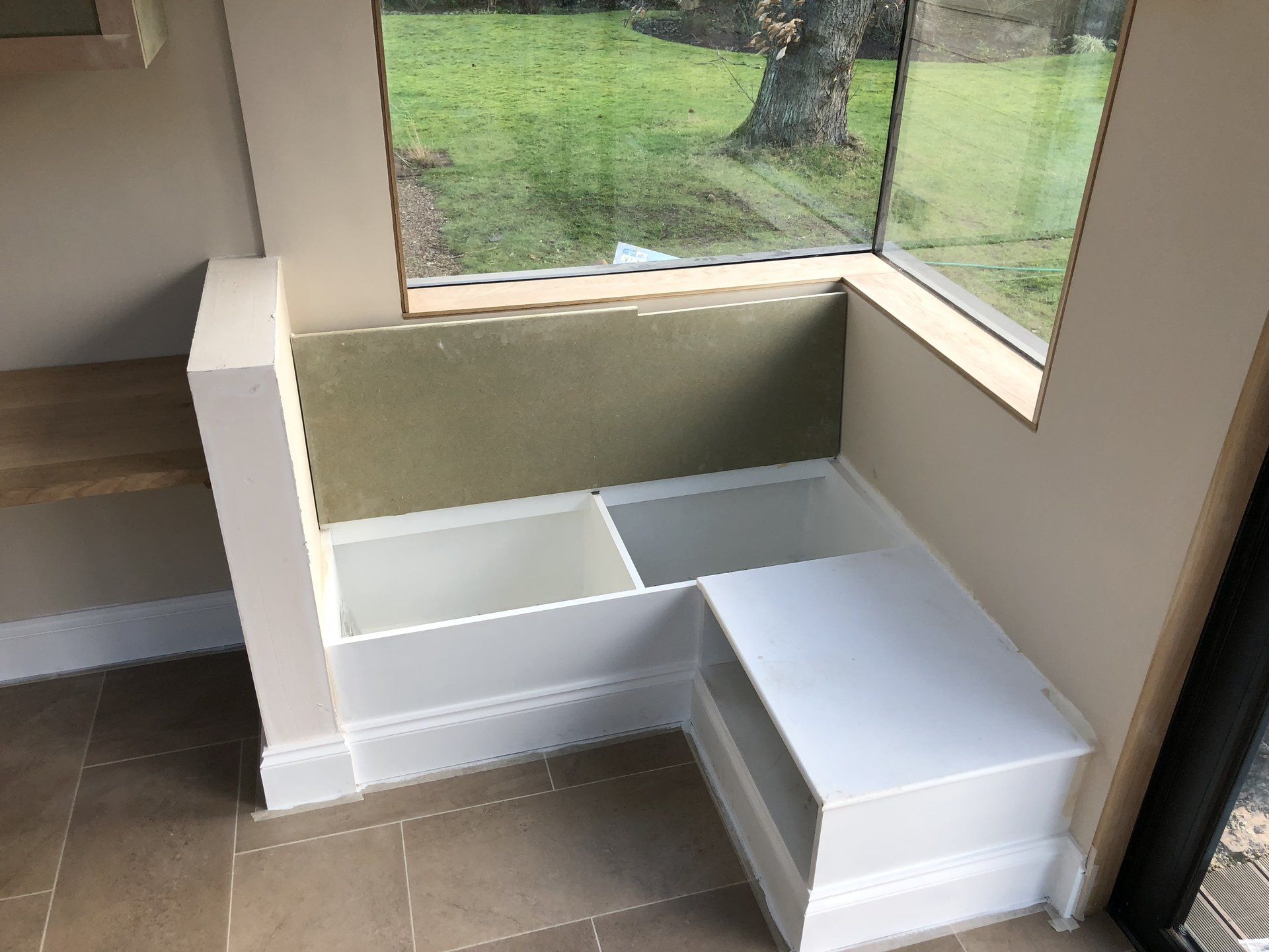 A corner of a room with a window and a bench.