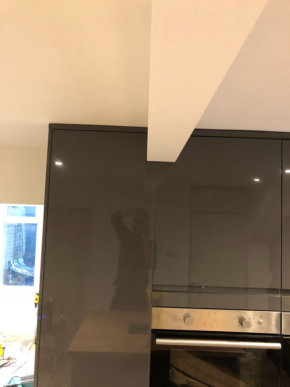 A kitchen with black cabinets and a stainless steel oven.