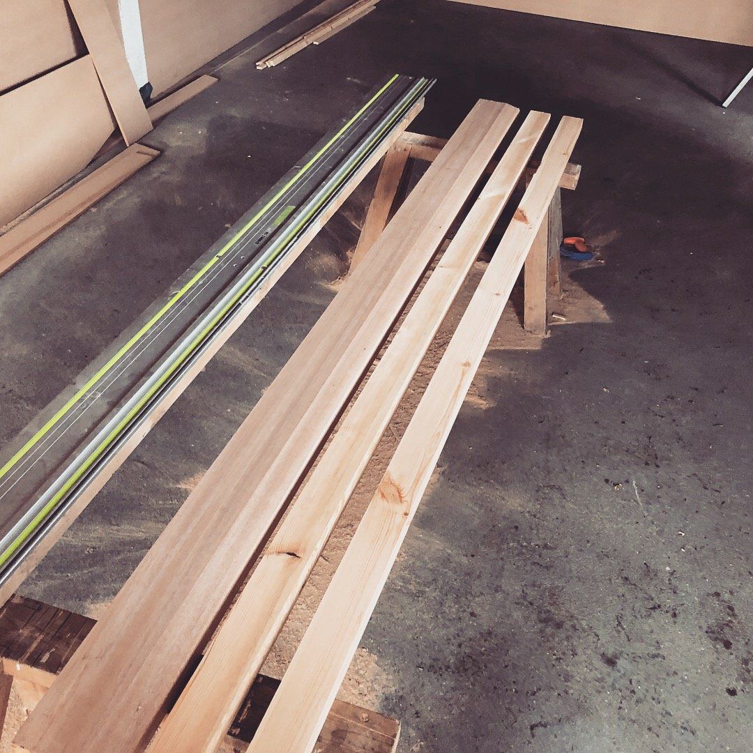 A wooden bench is sitting on the floor next to a ruler