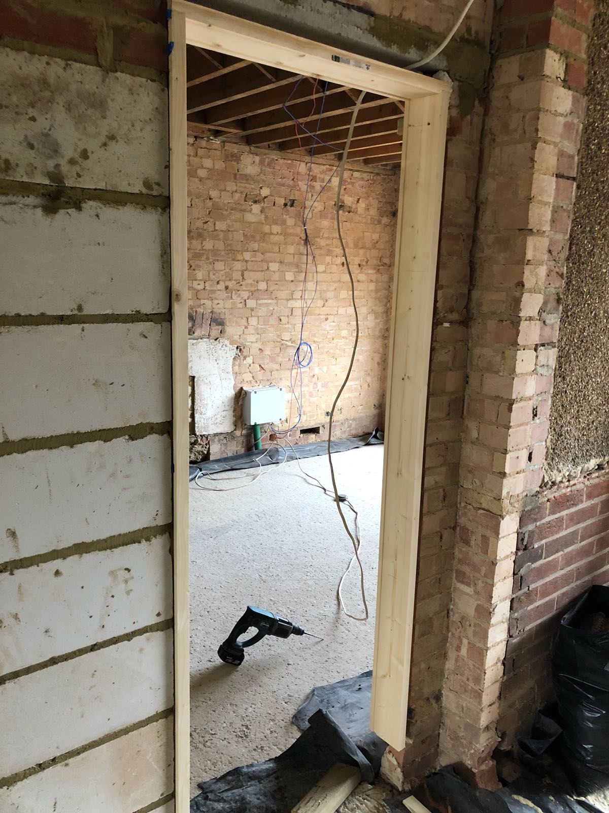 A door is being built into a brick wall in a room.