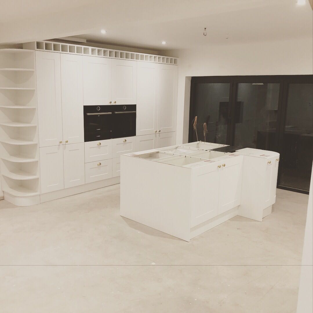 A kitchen with white cabinets and a large island in the middle.