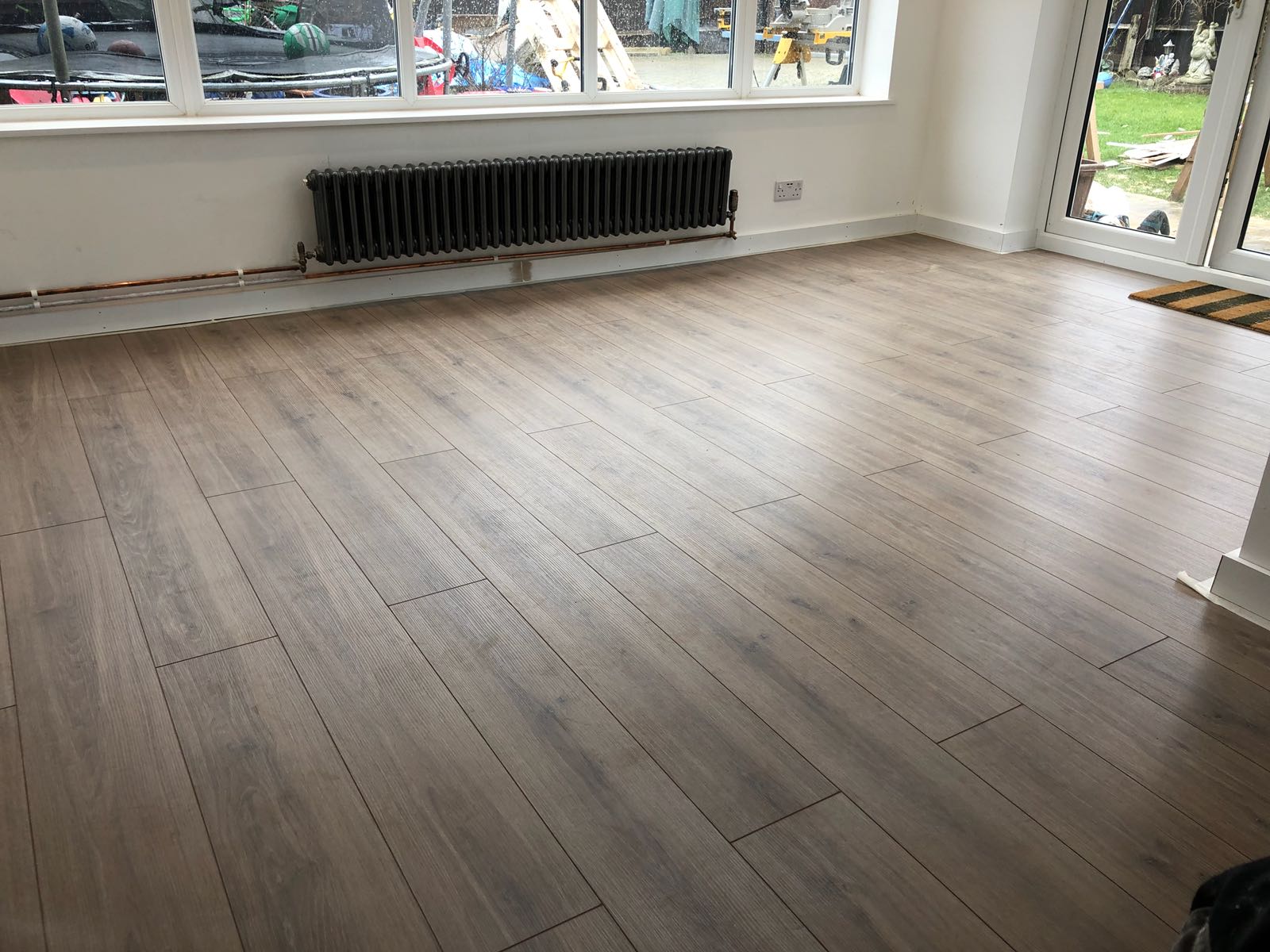 A living room with a wooden floor and a radiator.