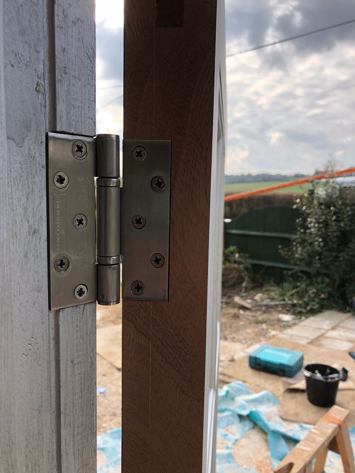 A close up of a door hinge on a wooden door.