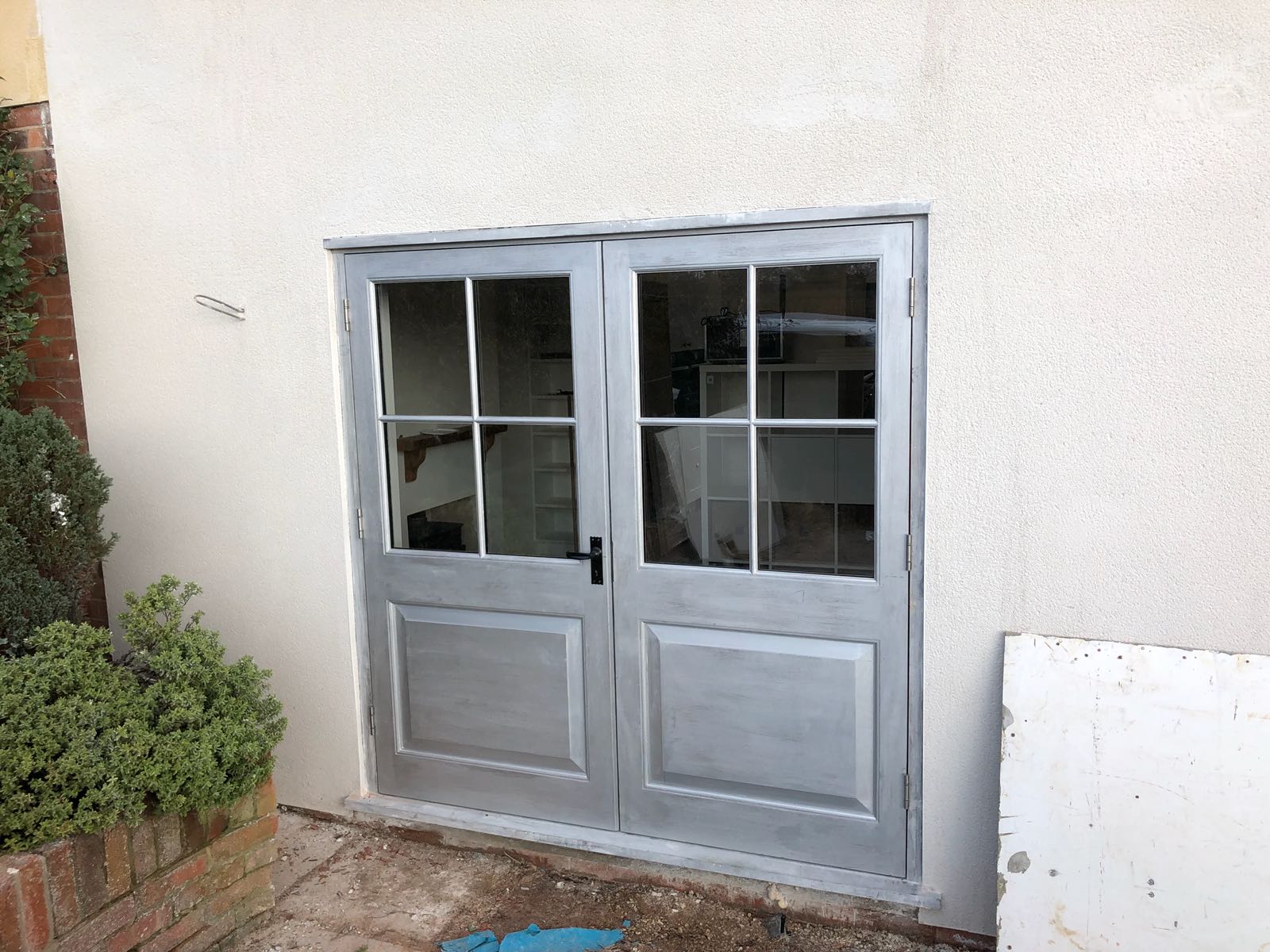 A pair of garage doors with a window on the side of a building.