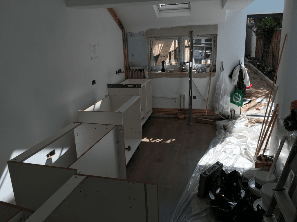 A kitchen under construction with a green bag on the floor