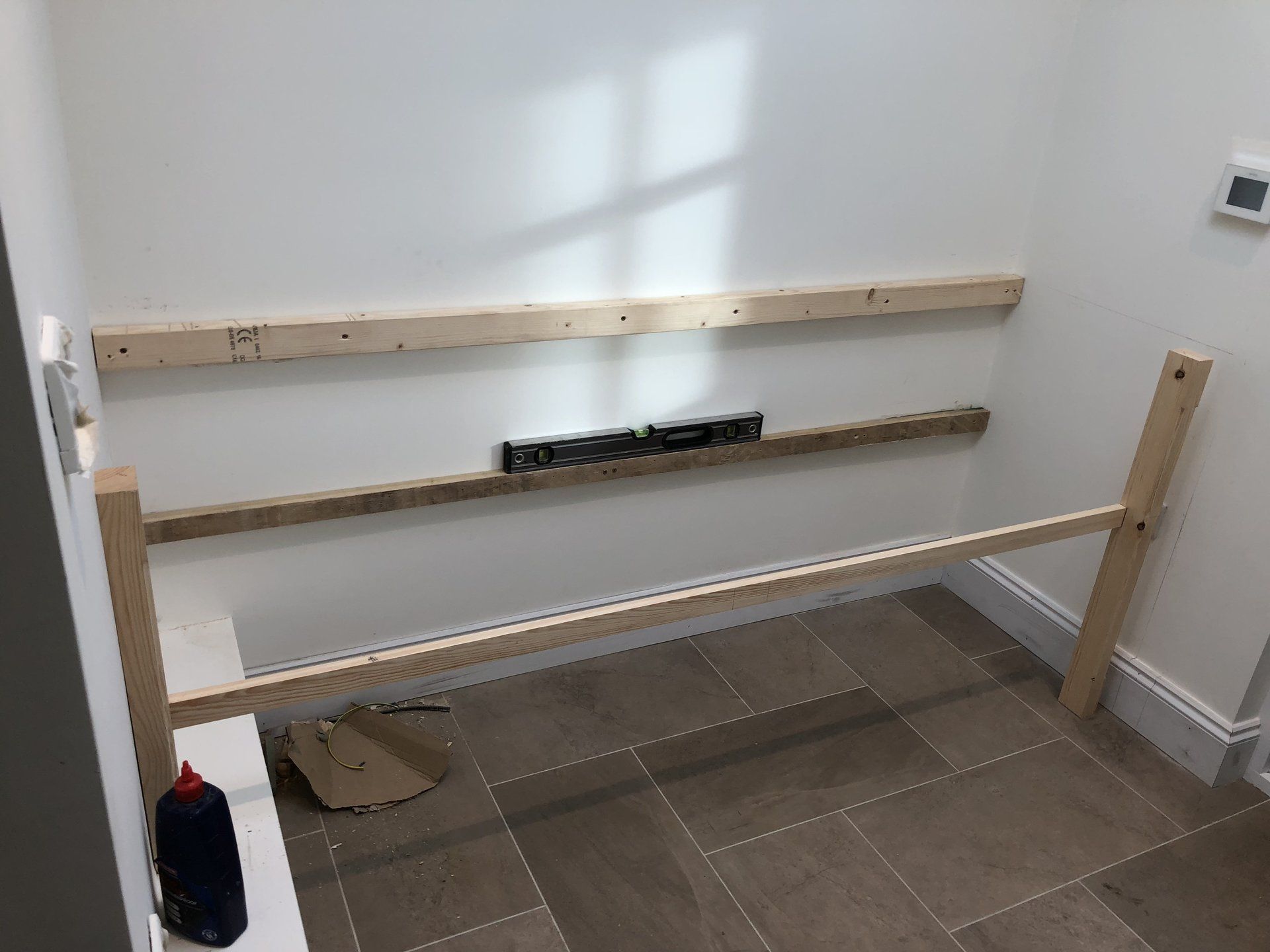 A wooden shelf is being built in a room.