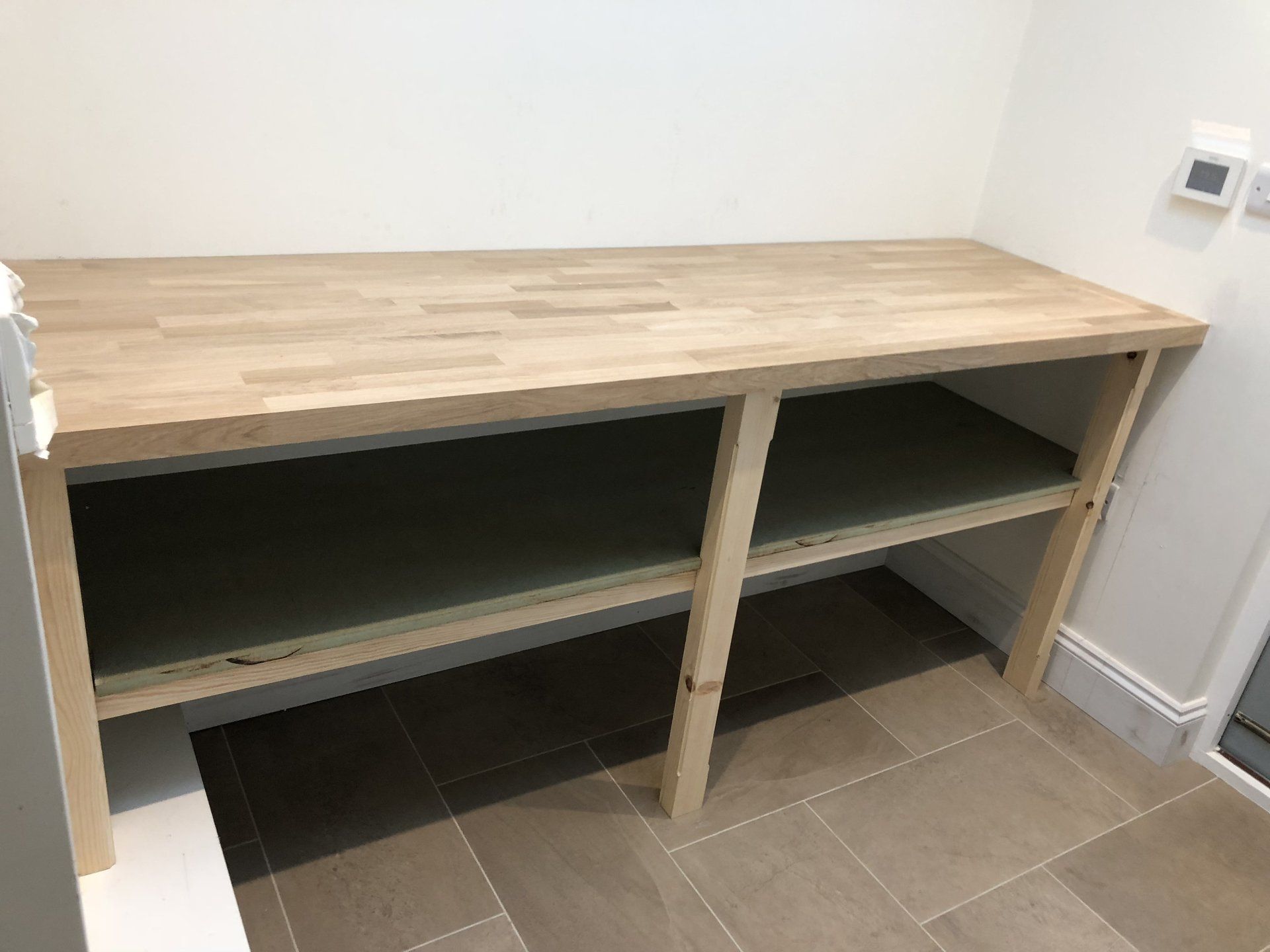 A wooden table with two shelves in a room.