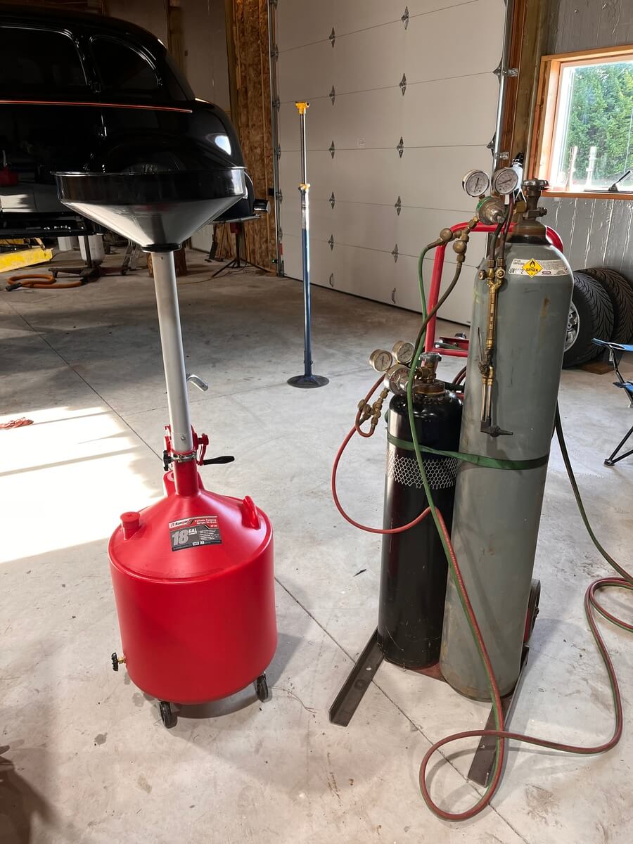 A red oil drain and a propane tank in a garage