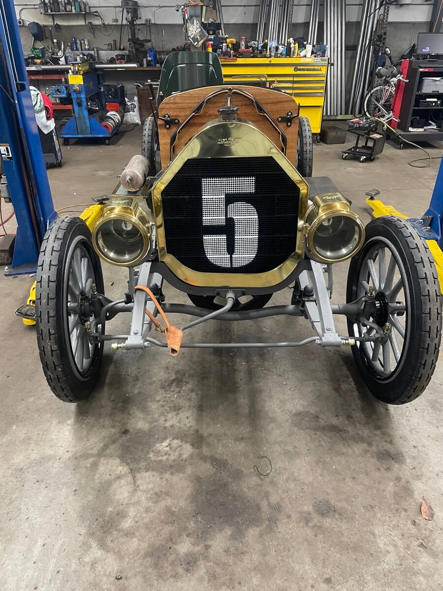 An old car with the number 5 on the front is in a garage.