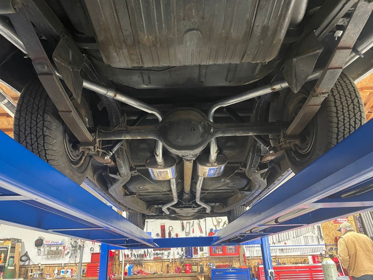 The underside of a car on a lift in a garage.