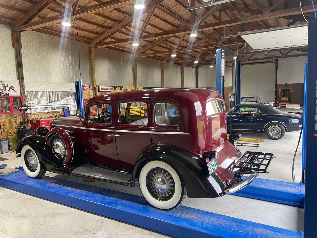 An old car is sitting on a lift in a garage.