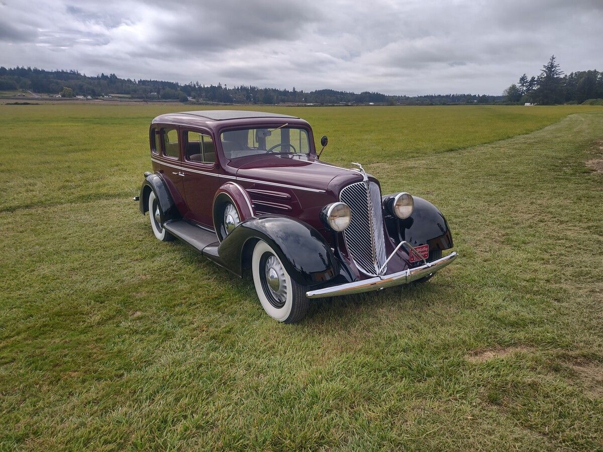 An old car is parked in a grassy field.