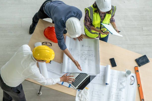 A group of construction workers are sitting around a table looking at blueprints.