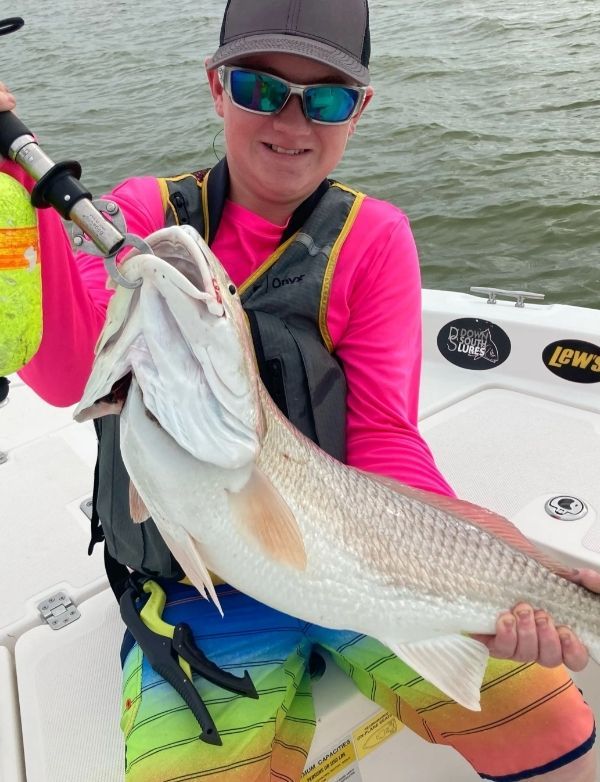A man on a boat holding a large fish