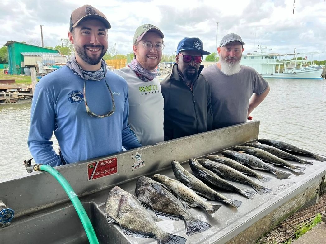 A group of men are standing next to a table full of fish.