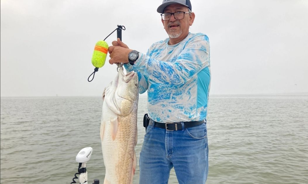 A man is standing on a boat holding a large fish.