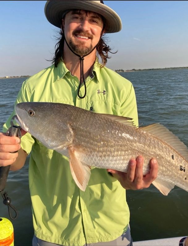 A man in a green shirt is holding a large fish
