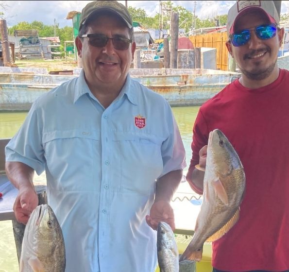 Two men are standing next to each other holding fish