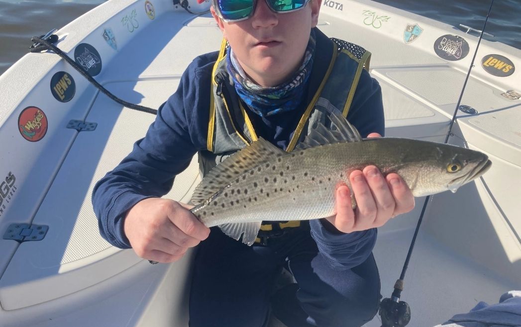 A young man is holding a fish on a boat.